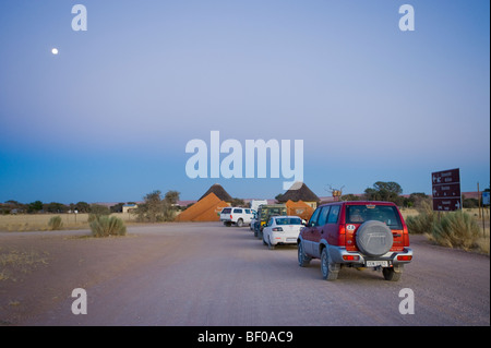 Autos warten am Sesriem Tor öffnen NAMIBIA Wüste SOSSUSVLEI am frühen Morgen Straße Dünen gelb rot orange Sand Staub breite l Stockfoto