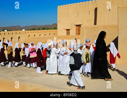 Lehrerin einer gemischten Schule Klasse von lebhaften jungen und Mädchen auf einen Ausflug in die Burg von Nizwa, Sultanat von Oman Stockfoto