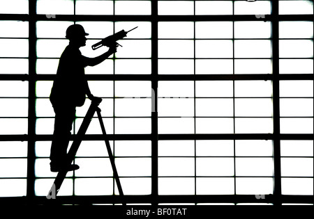 Ein Mann auf einer Leiter verleiht den letzten Schliff eine große undurchsichtige Wand in der Abflughalle im Flughafen von Glasgow, Schottland. Stockfoto