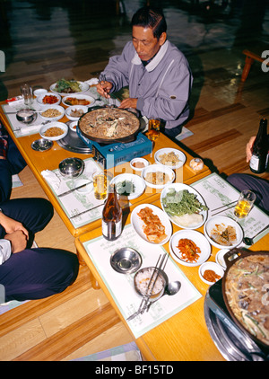 Südkorea-Mann isst Bulgogi (Korean Barbecue) umfasst verschiedene Arten von Gimchi als Beilagen Stockfoto