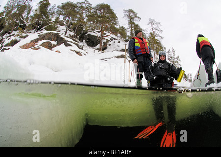 Schuss von Eistauchen, Eis Taucher sitzen auf das Eisloch, weißes Meer, Russland aufgeteilt Stockfoto