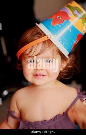 Lustige Bild eines 18 Monate alten Babymädchen tragen einen Kunststoff-Eimer auf dem Kopf Stockfoto