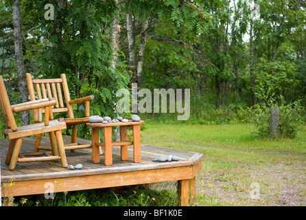 zwei Kiefer Log Stühle auf der Veranda mit Stapeln von gesammelten Felsen Stockfoto