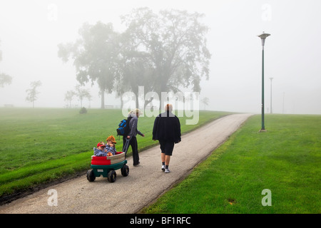 Mehr-Generationen-Familie an einem nebligen Morgen gehen, Assiniboine Park, Winnipeg, Manitoba, Kanada. Stockfoto