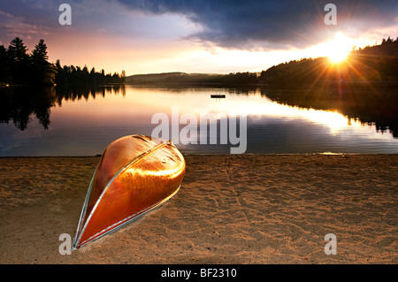 Sonnenuntergang über den ruhigen See mit Kanu am Strand Stockfoto