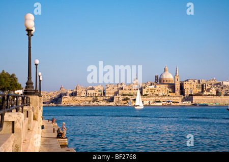 Menschen an der Strandpromenade von Sliema mit Blick auf die Stadt Valletta, Malta, Europa Stockfoto