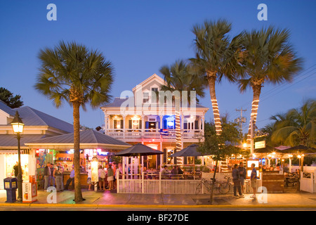 Leute sitzen auf der beleuchteten Terrasse einer Bar in der abends, Duval Street, Key West, Florida Keys, Florida, USA Stockfoto