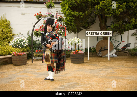 Kaukasischer schottischer Pfeifer, der vor dem Geschäft von Gretna Green Old Blacksmith, Schottland, Dudelsäcke spielt. VEREINIGTES KÖNIGREICH Stockfoto