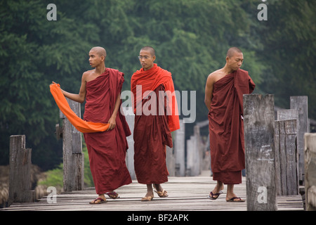 Drei junge buddhistische Mönche zu Fuß auf die U Klangkunst Bridgein Amarapura in der Nähe von Mandalay, Birma, Myanmar Stockfoto