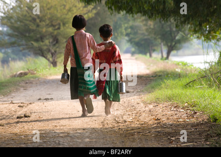 Zwei junge Schulmädchen von hinten zu Fuß auf Inwa Insel (Ava) am Ayeyarwady Fluß in der Nähe von Amarapura, Birma, Myanmar Stockfoto