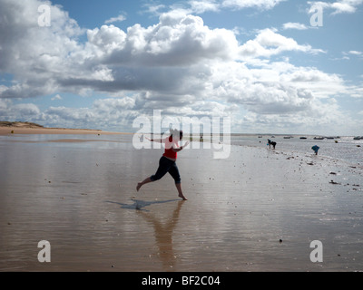 Eine Frau läuft bis zum Meer auf einem beatch Stockfoto