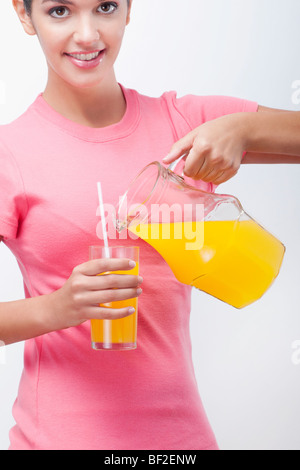 Porträt einer Frau, Orangensaft aus einem Krug gießen Stockfoto