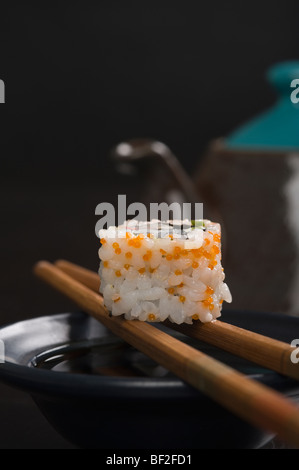 Nahaufnahme einer Maki-Sushi mit Stäbchen auf einer Schüssel Stockfoto