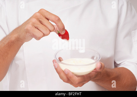 Mann eine Erdbeere in Creme Dippen Stockfoto