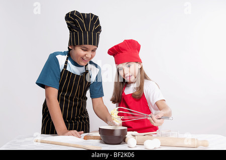 Junge geschlagener Eierteig mit seiner Schwester zu betrachten Stockfoto