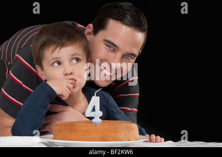 Porträt eines Mannes mit seinem Sohn hinter einer Geburtstagstorte Stockfoto