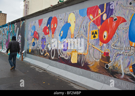 Neu übermalt Wandbild mit ein Mann zu Fuß vorbei an der Berliner Mauer an der East Side Gallery in Kreuzberg Berlin Stockfoto