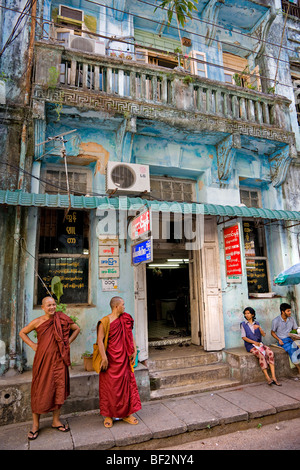 Zwei Mönche vor einem typischen alten Haus im Kolonialstil in Yangon, Myanmar. Stockfoto