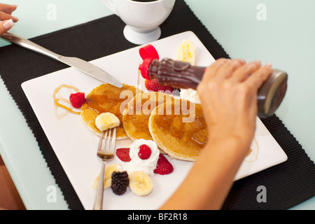 Nahaufnahme einer Person gießen Sirup auf Pfannkuchen Stockfoto