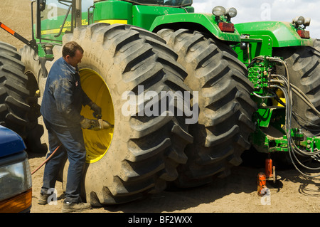 Ein Reifen-Techniker arbeitet, um einen Traktorreifen im Feld zu ändern, bei der Pflanzung Saison / Pullman, Palouse Region, Washington, USA. Stockfoto