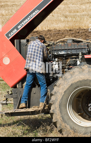 Ein Bauer führt Wartungsarbeiten an einem Traktor im Feld während der Pflanzsaison / in der Nähe von Pullman, Palouse Region, Washington, USA. Stockfoto