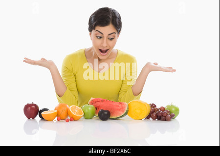 Frau mit Blick auf verschiedene frische Früchte und Gestikulieren Stockfoto