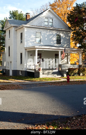 imposante weiß lackierten Schindeln Haus umrahmt von flammenden Laub & mit geräumigen Veranda unter amerikanischer Flagge Montgomery NY Stockfoto