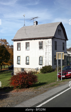 ehrwürdigen alten Haus mit niederländischen Dach & ungeschickt veränderten mit bemalten Weißasbest Abstellgleis auf sonnigen Herbsttag in Goshen, New York Stockfoto