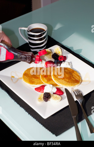 Person die Hand Gießen Sirup auf Pfannkuchen Stockfoto