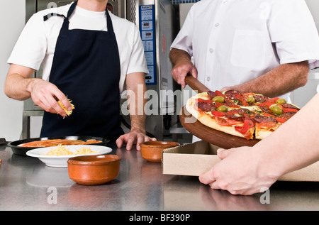 Drei Köche, die Pizza in der Küche vorbereiten Stockfoto