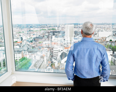 Geschäftsmann, Blick durch Fenster Stockfoto