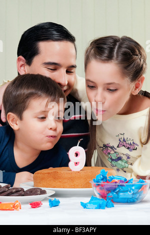 Junge und ein Mädchen mit ihrem Vater Geburtstagskerzen Ausblasen Stockfoto