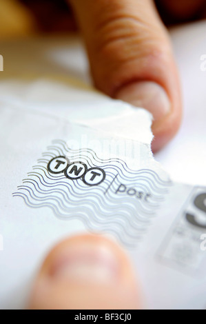 Ein Mann öffnet einen Brief von TNT geliefert Stockfoto