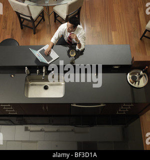 Asiatischer Mann Tippen auf Laptop in Küche Stockfoto