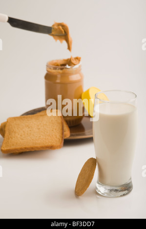 Erdnussbutter-Glas mit einem Glas Milch und Brot Scheiben Stockfoto