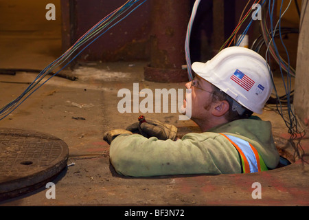 Chicago, Illinois - ein Angestellter im öffentlichen Dienst arbeiten an elektrischen Leitungen in einem Schacht. Stockfoto