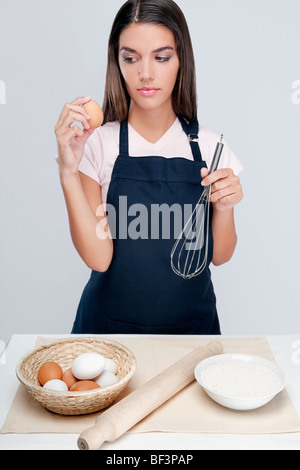 Frau hält ein Ei und Draht Schneebesen und denken Stockfoto