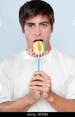 Porträt eines Mannes einen Lutscher lecken Stockfoto