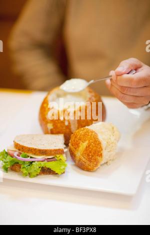 Mitte Schnittansicht eines Menschen essen Suppe aus einer Brotschale Stockfoto