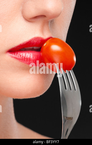 Nahaufnahme einer Frau Essen einer Kirschtomate Stockfoto