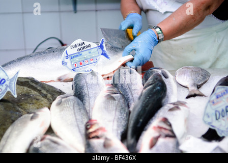 Fischhändler schneidet Lachs hinter Steinbutt (links) und Bass zum Verkauf an Fisch stall auf dem zentralen Markt Mercado Central Valencia Stockfoto