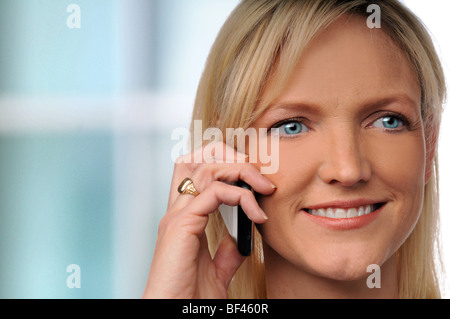 Lächelnde Geschäftsfrau mit Handy im Büro Stockfoto