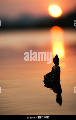 Silhouette der Buddha-Statue, die auf ruhigen stilles Wasser mit Sonnenaufgang in Indien schwimmende Stockfoto