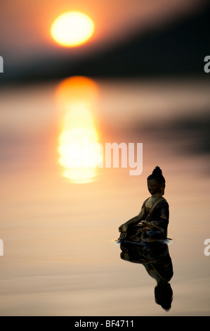 Silhouette der Buddha-Statue, die auf ruhigen stilles Wasser mit Sonnenaufgang in Indien schwimmende Stockfoto