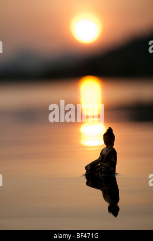 Silhouette der Buddha-Statue, die auf ruhigen stilles Wasser mit Sonnenaufgang in Indien schwimmende Stockfoto