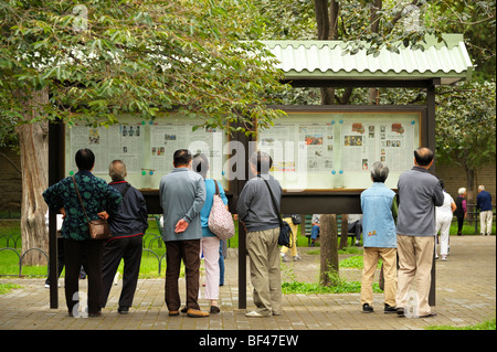 Eine Gruppe von älteren Menschen Lesen der Zeitung Anzeige in Tiantan Park, Beijing CN Stockfoto