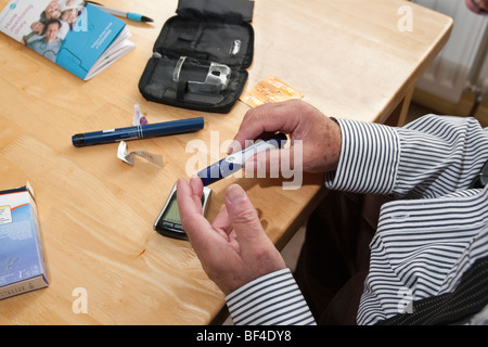 ältere männliche Diabetiker seine Blutzuckerwerte vor der Insulininjektion mit Accu-Chek Multiclix überprüfen Stockfoto