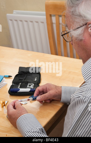 ältere männliche Diabetiker Vorbereitung zu seinen regelmäßigen Insulininjektion zu Hause mit Novomix Flexpen verwalten Stockfoto