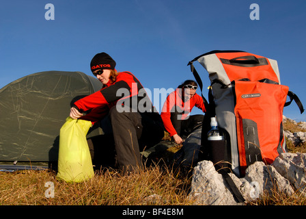 Wanderer, junger Mann und Frau das Aufstellen von einem Biwak mit Zelt, Schlafsack, Rucksack und schlafen-pad, Heidachstellwand, Rofan, A Stockfoto