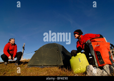 Wanderer, junger Mann und Frau das Aufstellen von einem Biwak mit Zelt, Schlafsack, Rucksack und schlafen-pad, Heidachstellwand, Rofan, A Stockfoto